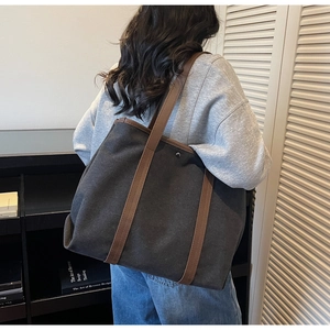Deep charcoal canvas tote bag with contrast brown leather straps shown in a lifestyle setting