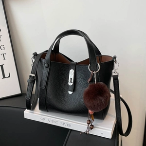 Détail du sac seau noir en cuir grainé avec fermoir argenté et pompon décoratif