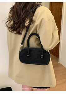 Rear view of model wearing beige coat with a minimalist black crossbody pillow bag