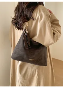 Detail of a dark brown matte leather tote bag with gold hardware and small side pouch