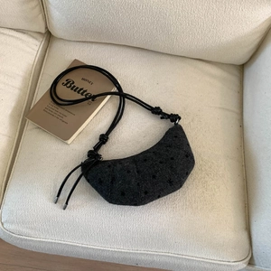 Détail du sac croissant noir avec jacquard à pois et bandoulière à nœuds élégante