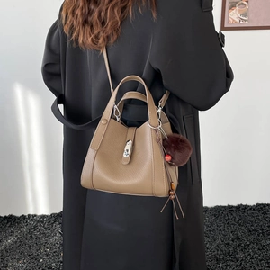 Détail du sac seau en cuir grainé kaki avec fermoir métallique et breloque pompon
