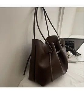 Macro shot of dark brown tote bag showing wrinkled leather texture and drawstring detail