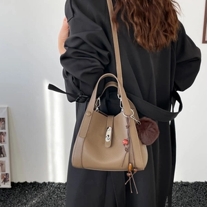 Détail du sac seau en cuir grainé avec fermoir métallique et pompon en peluche