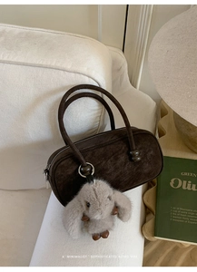 Detailed view of vintage dark brown cylindrical Boston bag with cute plush bunny charm