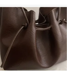 Close-up of soft brown leather texture and drawstring detail on large tote bag