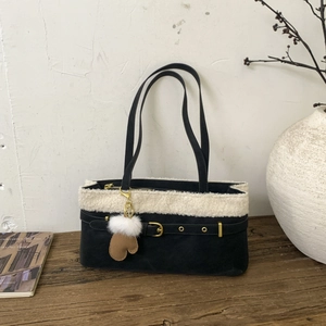 Detail of black suede tote with white faux fur trim, gold buckle, and glove charm