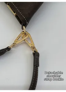 Detail of gold lobster clasp on brown pebbled leather bag with detachable shoulder strap