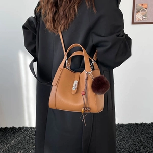 Sac seau en cuir grainé marron avec boucle métallique argentée et pompon décoratif