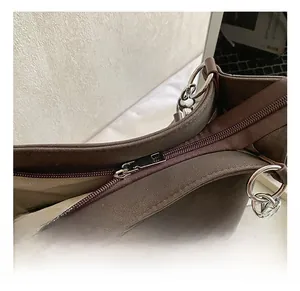 Close-up of durable metal zipper and ring hardware on brown suede leather tote bag