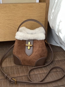 Borsa a secchiello in camoscio marrone con bordo in ecopelliccia bianca e tracolla dorata