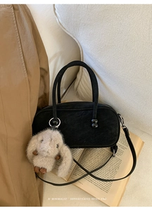 Detail of vintage black matte Boston bag with plush rabbit charm and adjustable strap