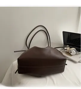 Detail view of large brown soft leather tote bag on desk with modern office accessories