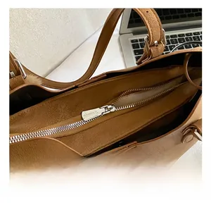 Close-up of the smooth silver zipper closure and leather texture on a brown tote bag