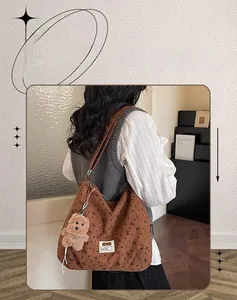 Detailed texture of brown corduroy tote bag with black bow prints and plush dog charm