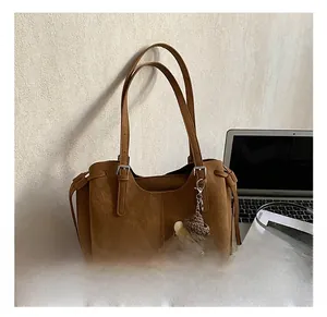 Detailed shot of brown matte tote bag with thin straps and cute plush pendant decoration