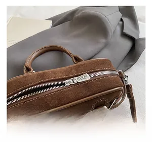 Close-up of premium silver zipper and brown suede texture on a minimalist baguette bag