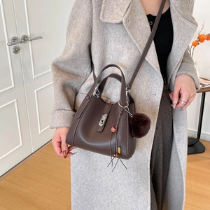 Détail du sac seau en cuir grainé marron foncé avec fermoir argenté et breloque