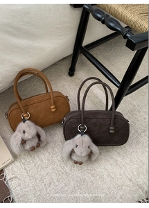 Detail view of retro Boston handbags in brown and coffee with plush rabbit charms
