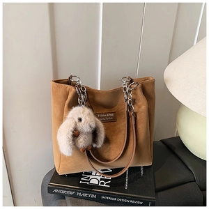 Detail of vintage brown tote bag with metal chain strap and plush rabbit charm accessory