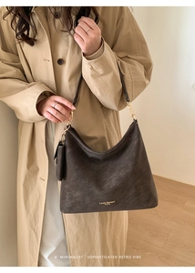 Detail of dark brown leather tote bag showing fine texture and gold hardware accents