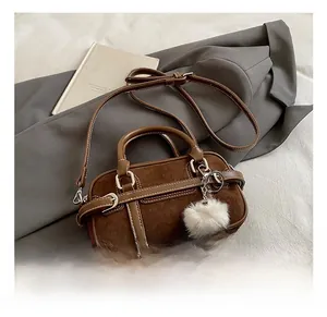 Detail of dark brown bowling bag with suede stitching and decorative plush charm