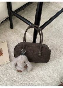 Detail of vintage dark brown Boston bag with a cute plush bunny charm on a soft rug