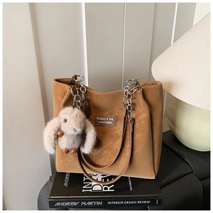 Detailed view of brown suede tote bag with metal chain strap and cute bunny pendant