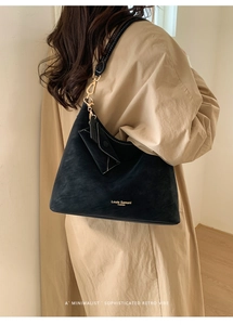 Detail of black suede tote bag with metal hardware and matching envelope pouch