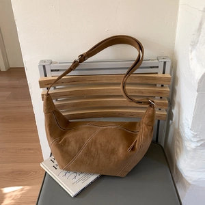 Gros plan d'un sac bandoulière demi-lune marron avec surpiqûres blanches contrastées