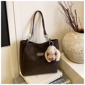 Detailed view of dark brown tote bag with litchi texture and cute plush rabbit charm