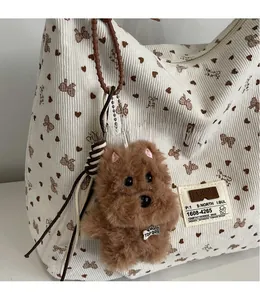 Détail d'un pendentif chien en peluche sur un sac cabas en velours à motifs cœurs