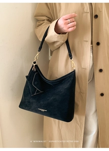 Detail of matte black tote bag with small detachable pouch and gold hardware accents