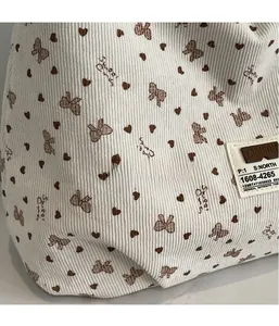 Détail du sac cabas en velours côtelé blanc cassé avec imprimé cœur et étiquette mode