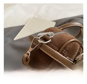 Detail shot of silver zipper and metal hook on dark brown suede baguette handbag