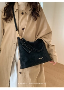 Detail of black suede tote bag featuring white contrast stitching and gold hardware