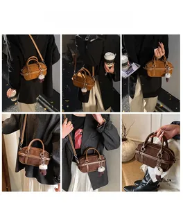 Detail of vintage suede Boston bag with plush ball charm and adjustable shoulder strap
