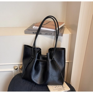 Close-up of black leather tote bag featuring elegant drawstring details and lychee texture
