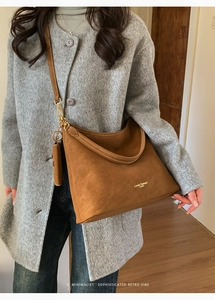Detail of brown suede hobo bag with gold logo on a grey wool coat background