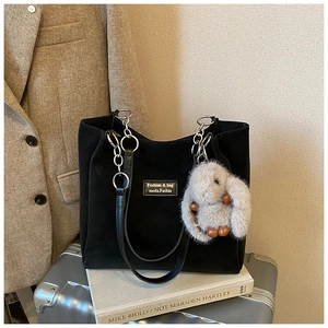 Detail of black tote bag with silver chain strap and a cute grey plush rabbit pendant