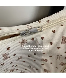 Détail du sac en velours côtelé écru avec imprimé nœud et fermeture éclair en métal poli