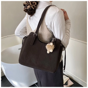 Detail of mocha matte leather tote bag featuring vertical stitching and a plush charm