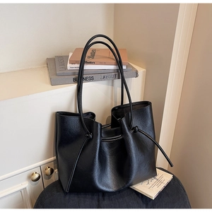 Close-up of large black tote bag featuring textured faux leather and side drawstring detail