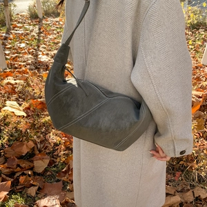 Détail du sac demi-lune en daim avec surpiqûres contrastées sur manteau en laine