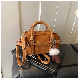 Detail of a brown Boston bag with suede stitching and decorative plush glove charms