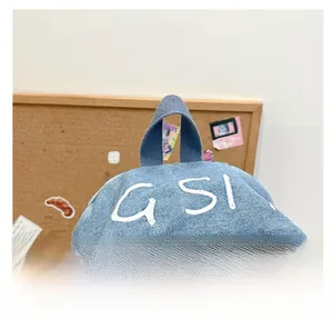 Close-up of blue denim backpack showing top handle and white GSI embroidery detail
