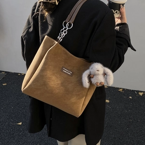 Detail of a brown suede tote bag with silver chain strap and a cute rabbit pendant