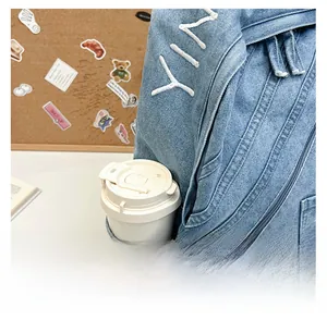 Detail view of side pocket on blue denim backpack featuring white YI embroidery and a cup