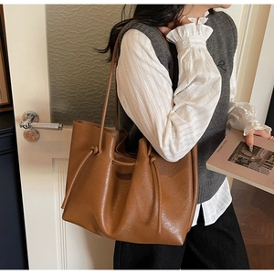 Detailed close-up of brown leather tote bag with knotted drawstring handle detail