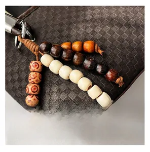 Close-up of bohemian beaded charm with wooden beads on a woven leather bucket bag